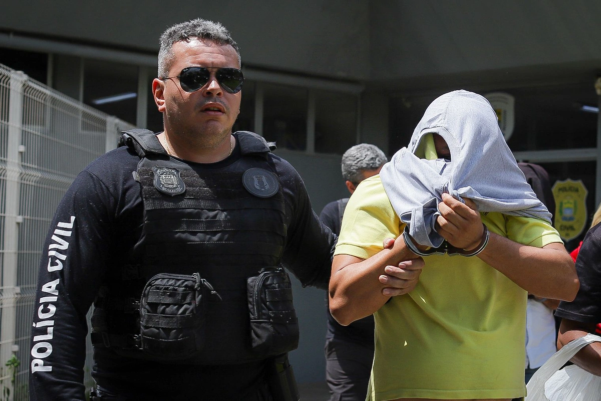 Empresário sendo conduzido por policial do DHPP