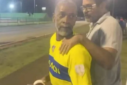 Homem de amarelo, preso enquanto particiapava de partida de futebol amador, por arrastar filha presa em carro no RJ