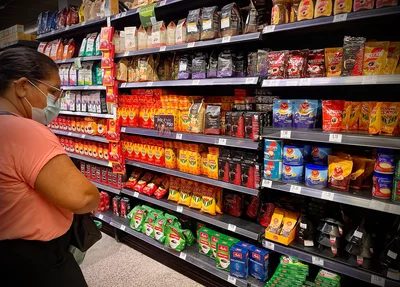 Mulher verificando o preço do café nas prateleiras do supermercado