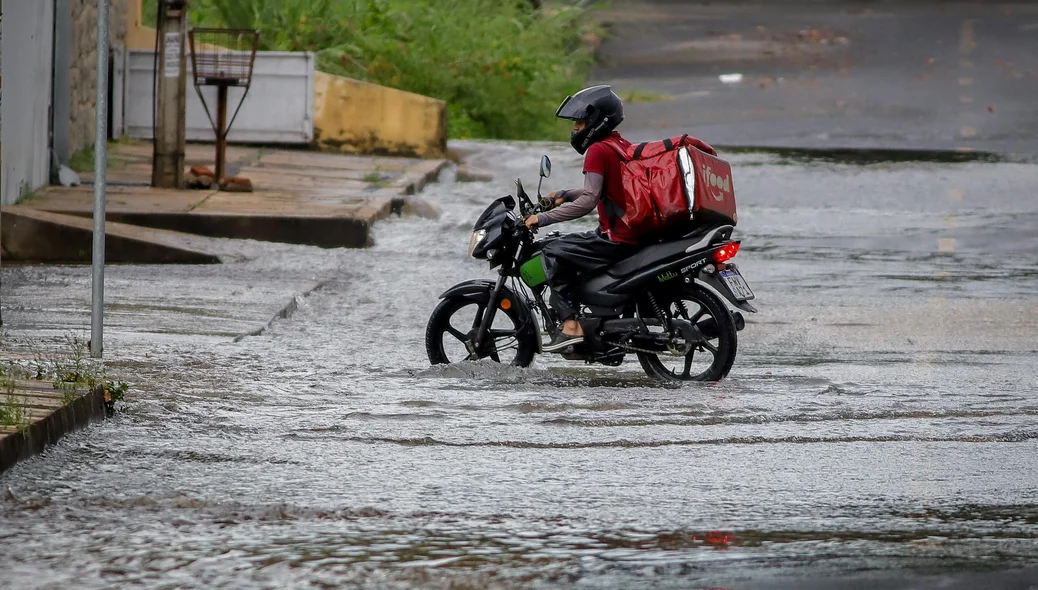 Motociclista de aplicativo tentando passar por via alagada