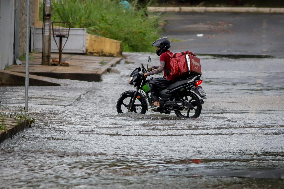 Motociclista de aplicativo tentando passar por via alagada