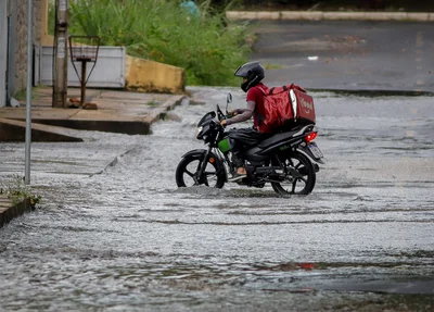 Motociclista de aplicativo tentando passar por via alagada