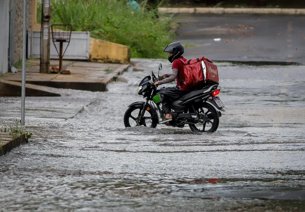 Motociclista de aplicativo tentando passar por via alagada