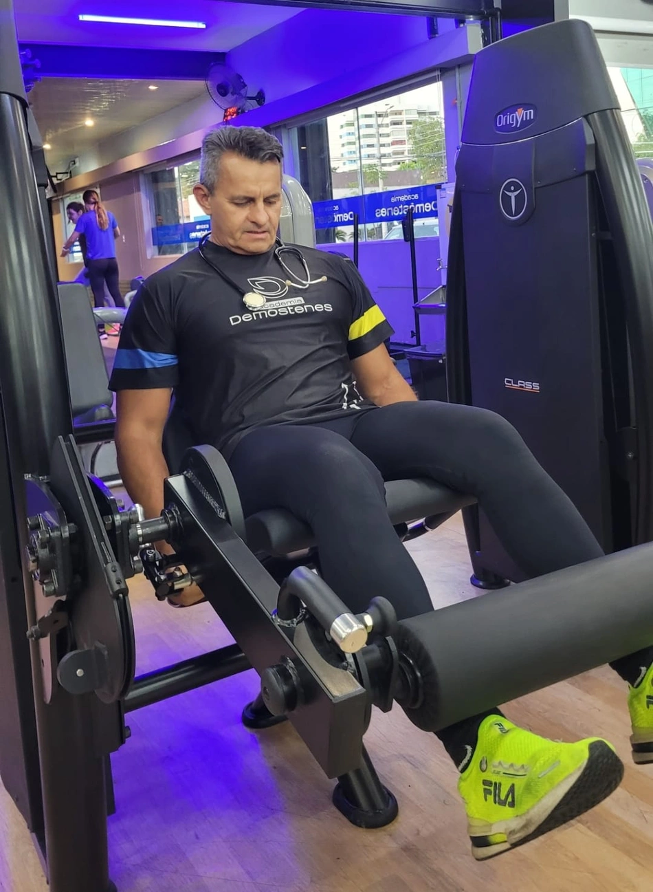 Professor Demóstenes demonstra equipamento para fortalecer as pernas