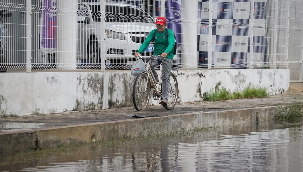 Ciclista passa pela calçada para evitar enfrentar alagamento