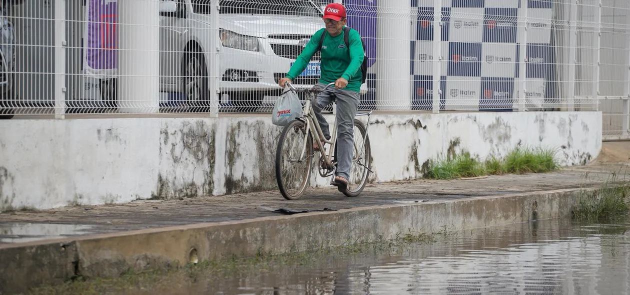 Ciclista passa pela calçada para evitar enfrentar alagamento