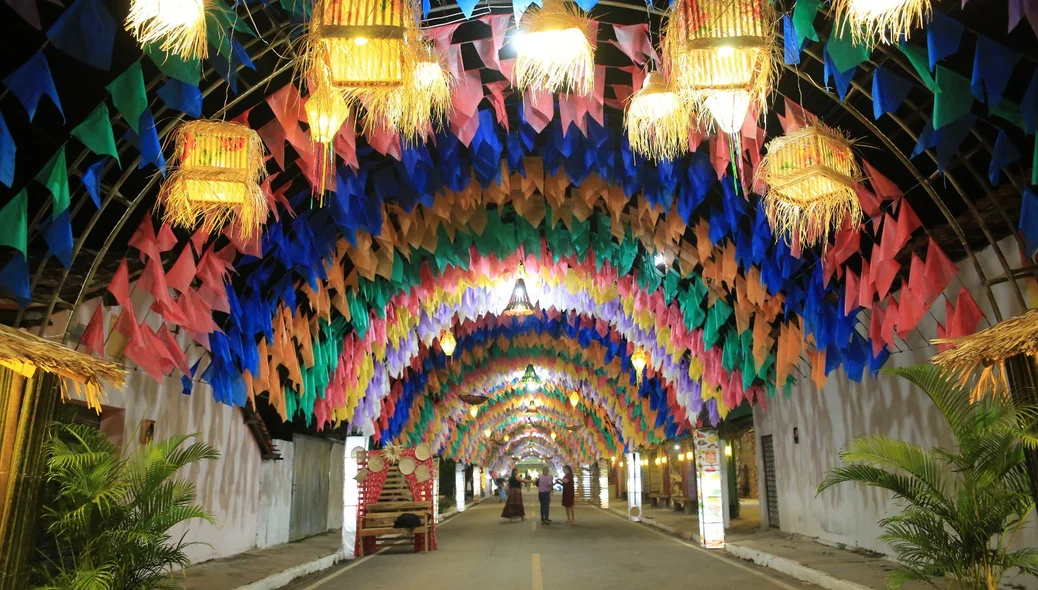 Rua decorada com bandeirolas coloridas e luminárias de palha anuncia o clima festivo do XXI Festival Cultural dos Cocais em São João do Arraial