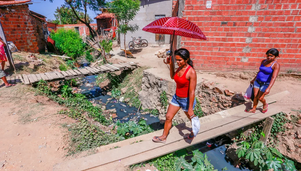 Moradores atravessam ponte feita por moradores para chegar em suas residências