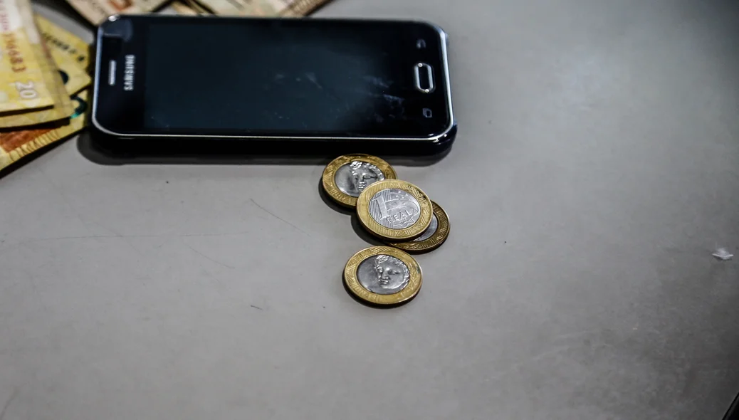 Celular e moedas apreendidas 