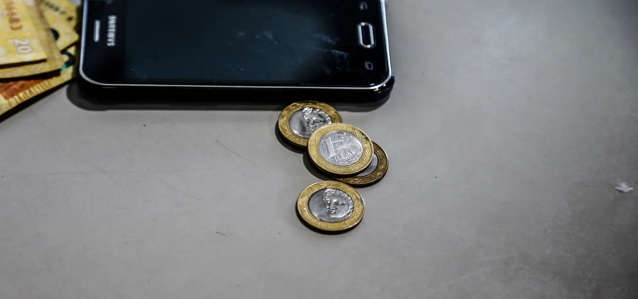 Celular e moedas apreendidas 