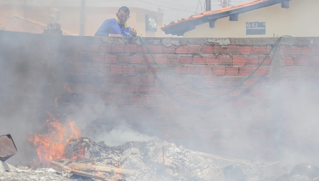 Morador tentando apagar o fogo com água da mangueira 