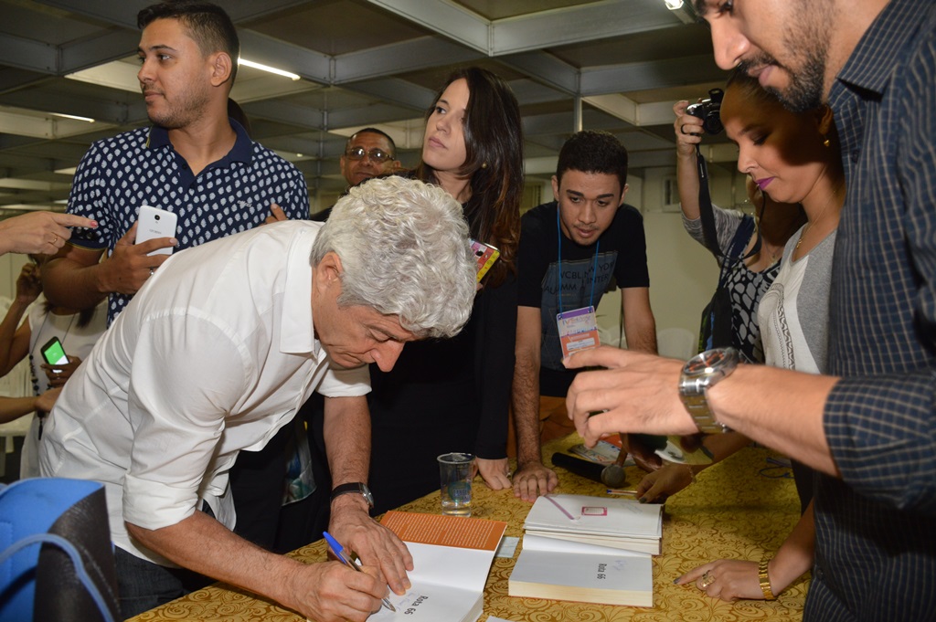 Jornalista autografa livros.