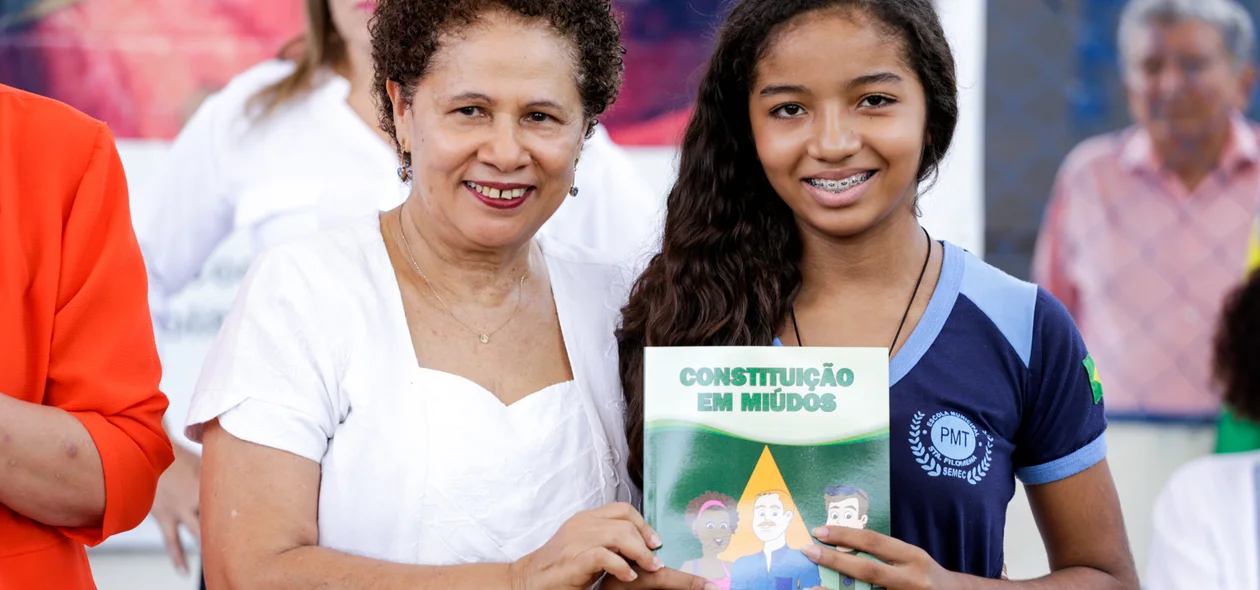 Regina Sousa entrega livro para aluna