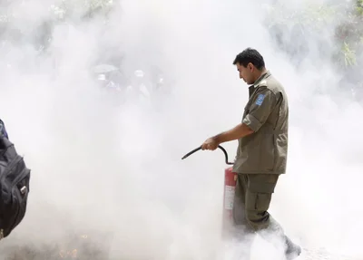 Policial militar tentando apagar o fogo em frente a Alepi