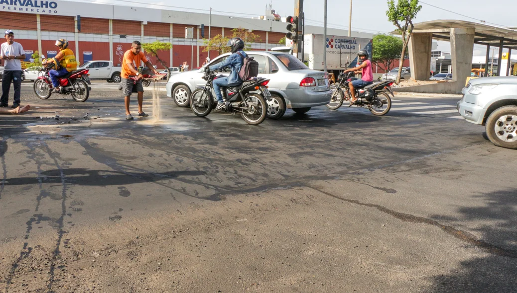 Populares jogando areia na pista para neutralizar o óleo derramado