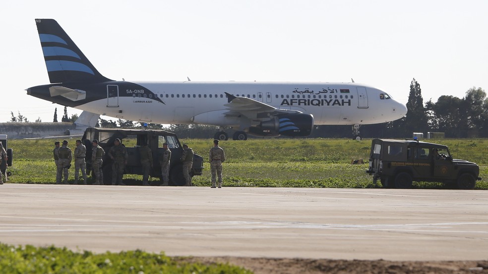Tropas acompanham a inspeção do avião no aeroporto de Malta