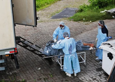 Funcionários do Instituto Médico Legal (IML) colocam corpos de presos em um caminhão