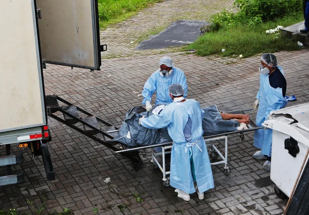 Funcionários do Instituto Médico Legal (IML) colocam corpos de presos em um caminhão