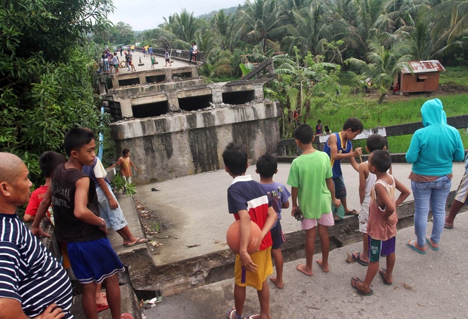 Populares observam ponte que caiu após terremoto atingir a cidade de Surigao