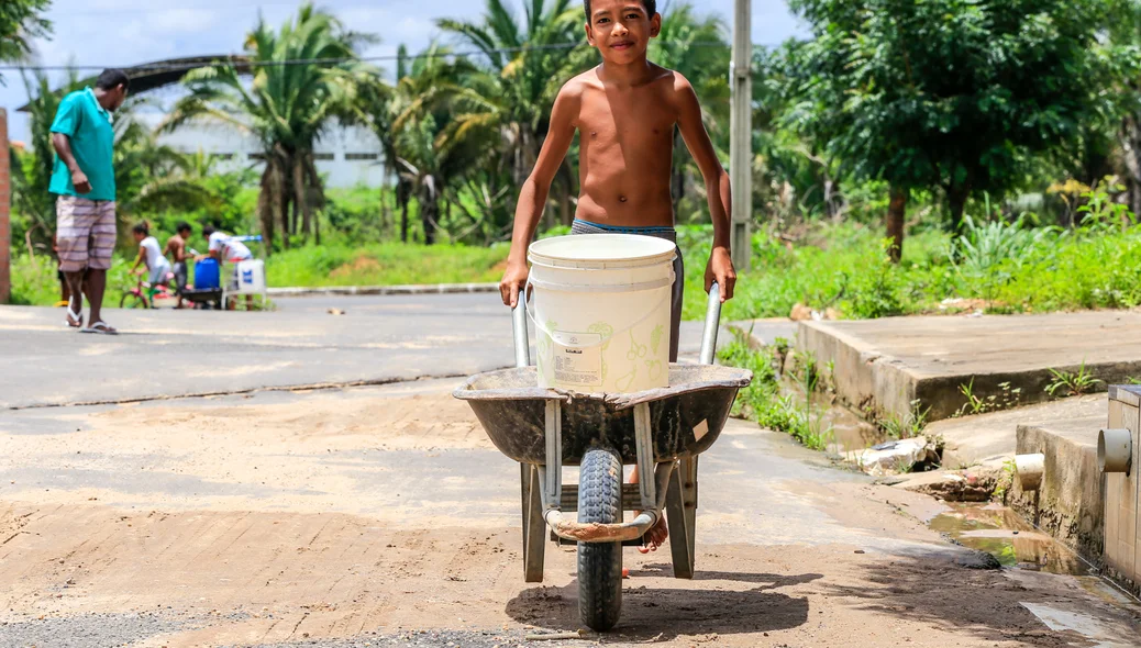 Criança carregando água para sua casa