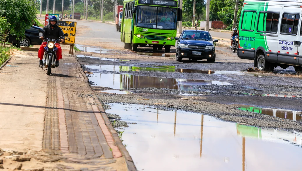 Motoqueiro passa por cima da calçada por causa dos buracos na avenida