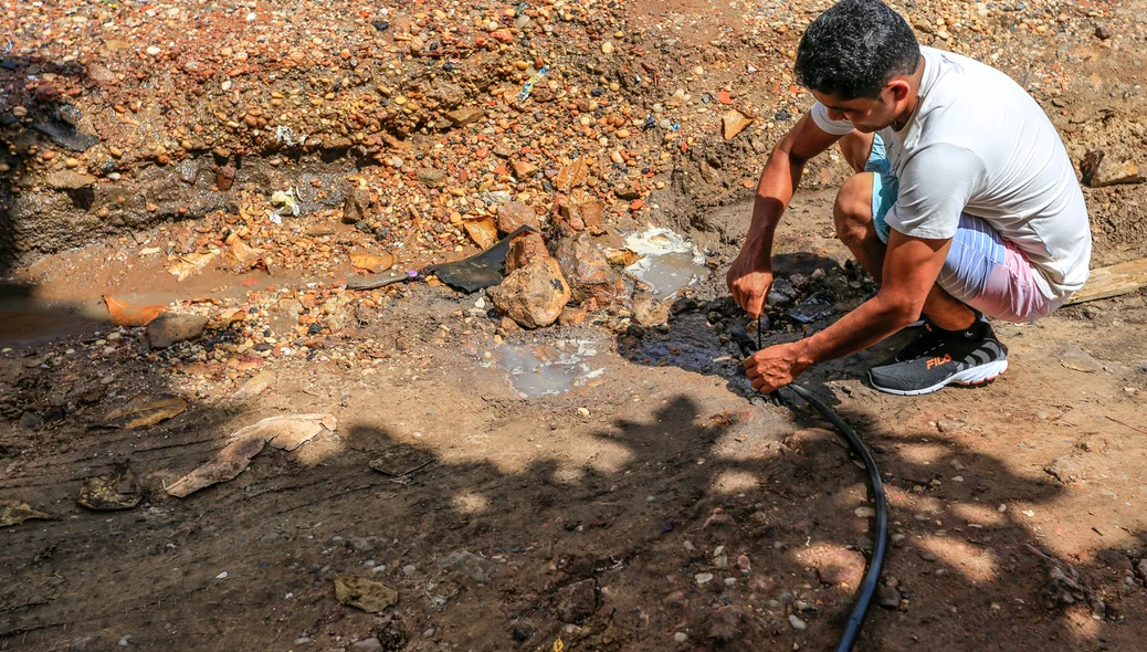 Morador tentando ajeitar o vazamento de água