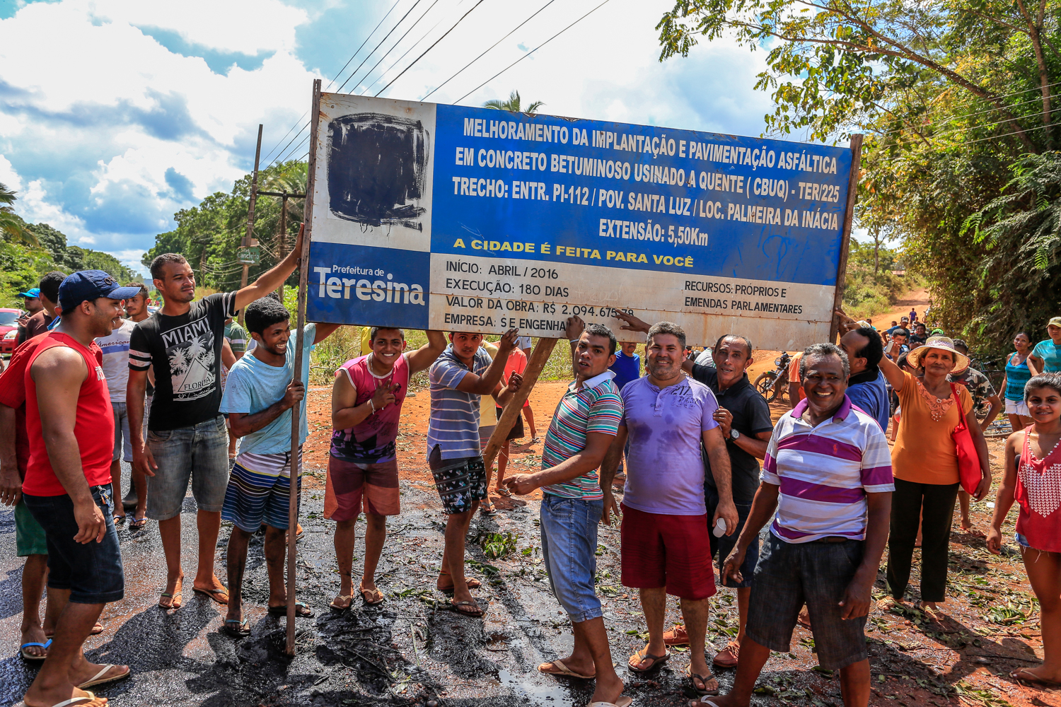 Moradores mostram a placa de melhorias no povoado 