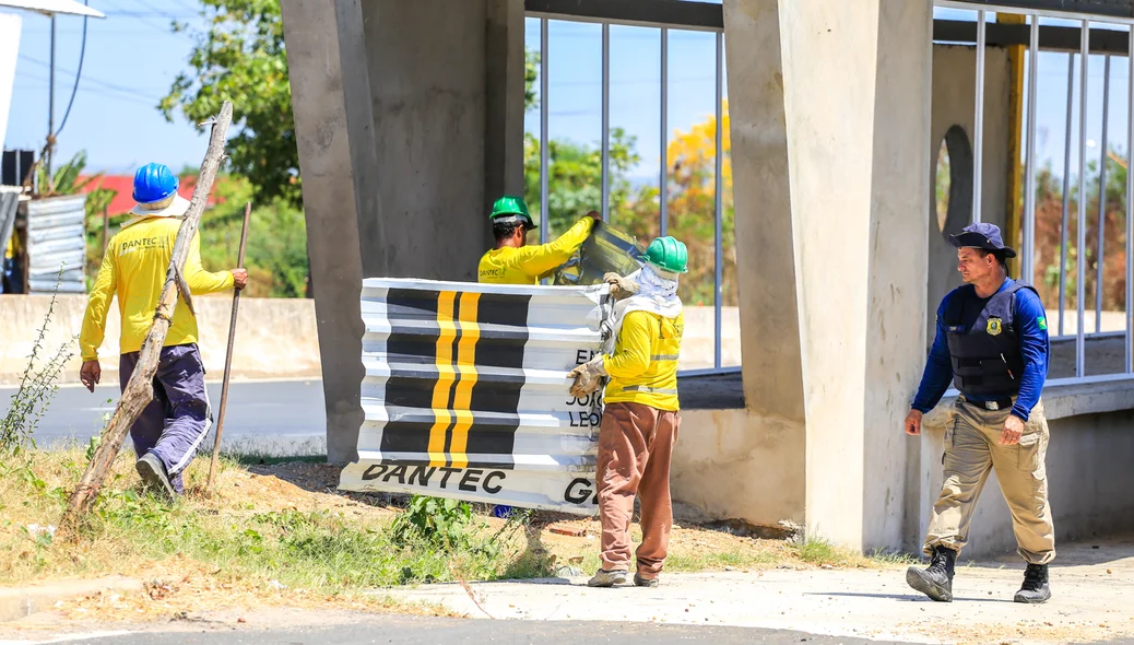 Funcionários retirando placas da obra