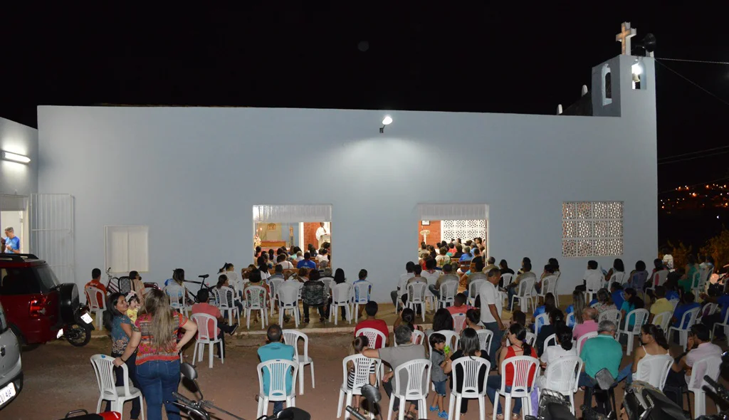 Várias pessoas assistem a missa do lado de fora da igreja