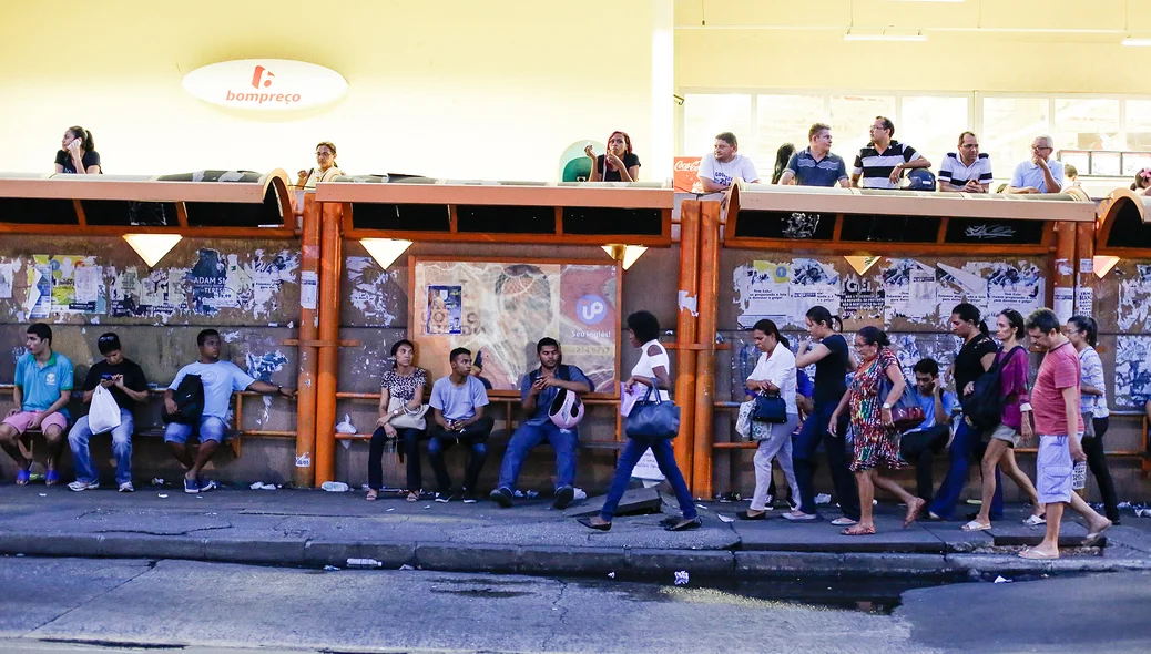 Pessoas aguardam ônibus na parada