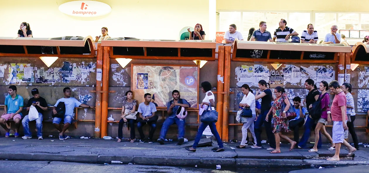 Pessoas aguardam ônibus na parada