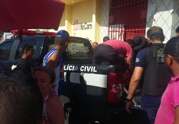 Corpo sendo transportado em viatura da polícia 