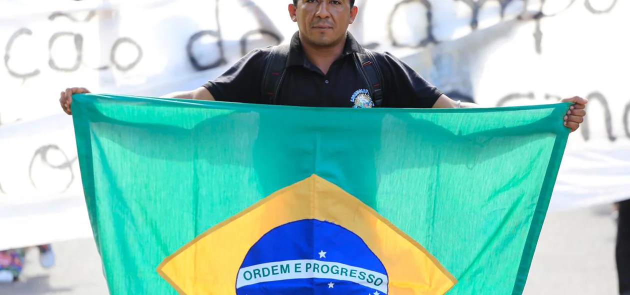 Manifestante segura bandeira do Brasil durante ato na reitoria da UFPI