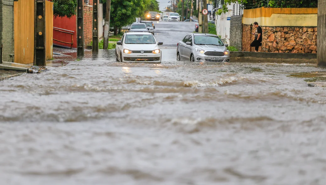 Veículos têm dificuldade em passar pela via alagada