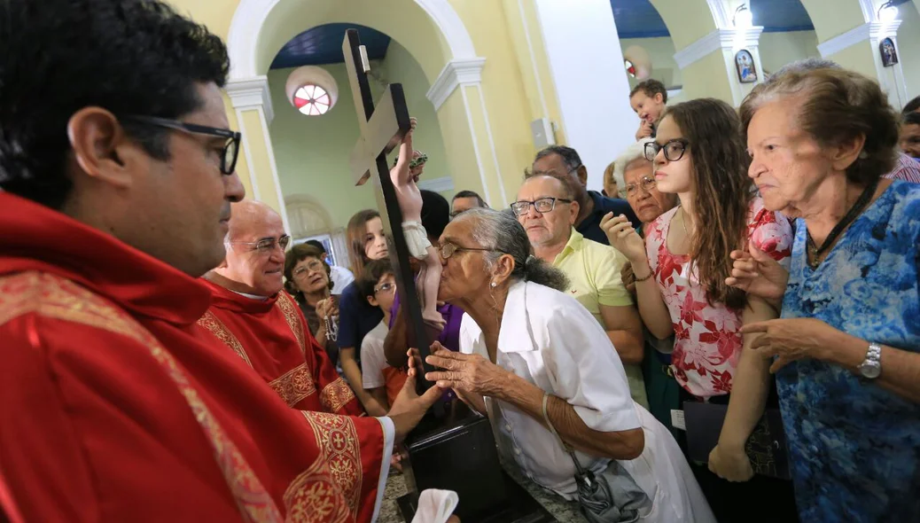 Fiéis beijam os pés de Jesus em cruz