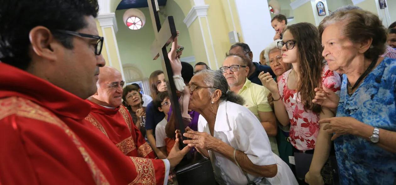 Fiéis beijam os pés de Jesus em cruz