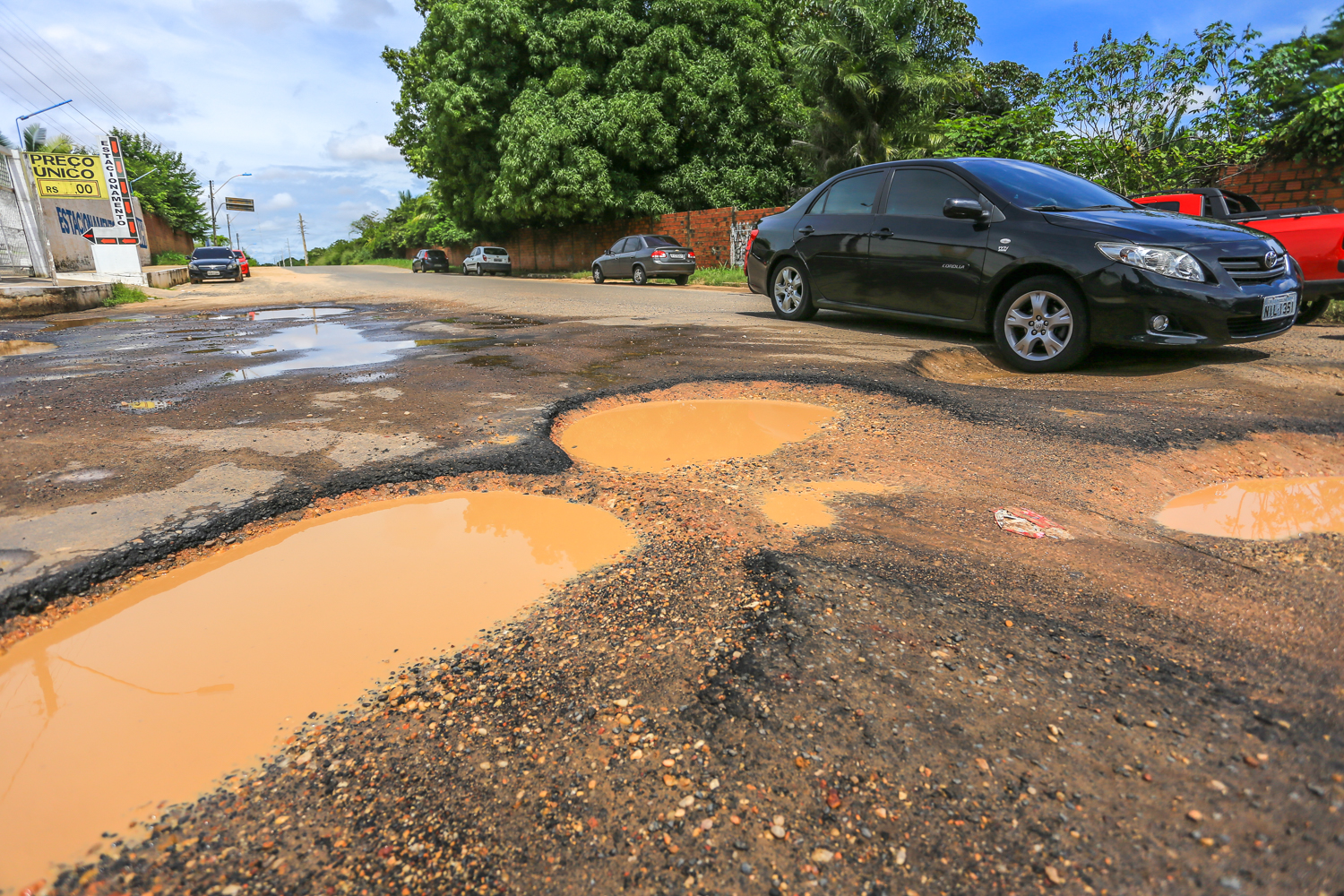 Carro passa pelo buraco com dificuldades
