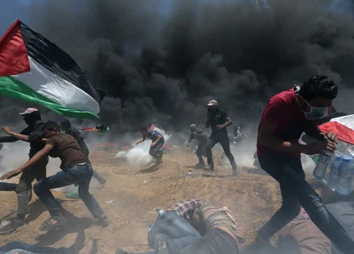 Manifestantes palestinos correm para se proteger de tiros e bombas de gás