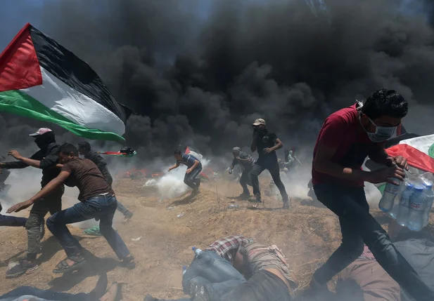 Manifestantes palestinos correm para se proteger de tiros e bombas de gás
