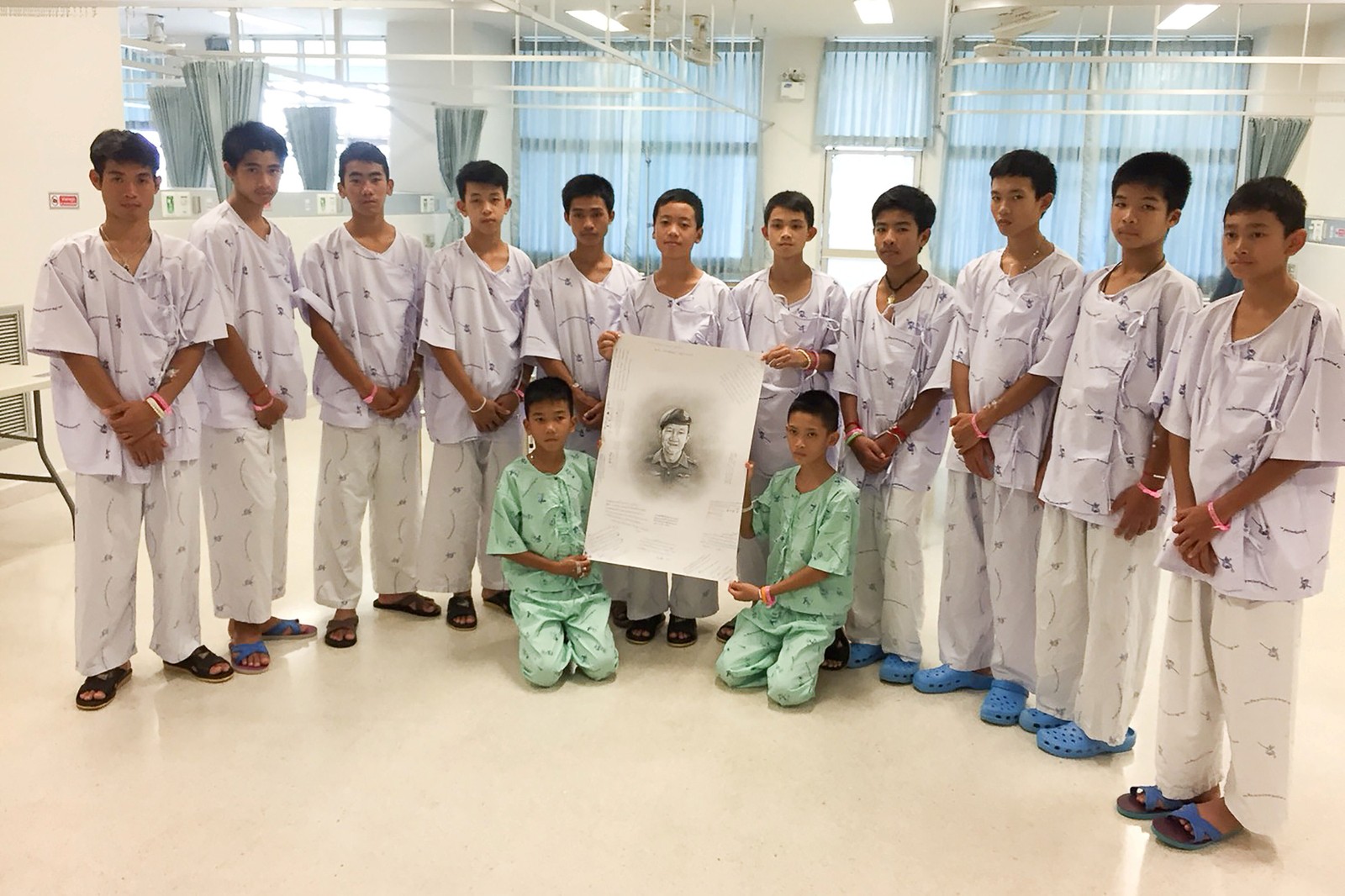 Os 12 meninos resgatados posam com um desenho do mergulhador Saman Kunan