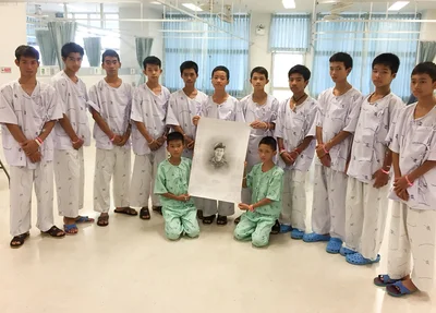 Os 12 meninos resgatados posam com um desenho do mergulhador Saman Kunan