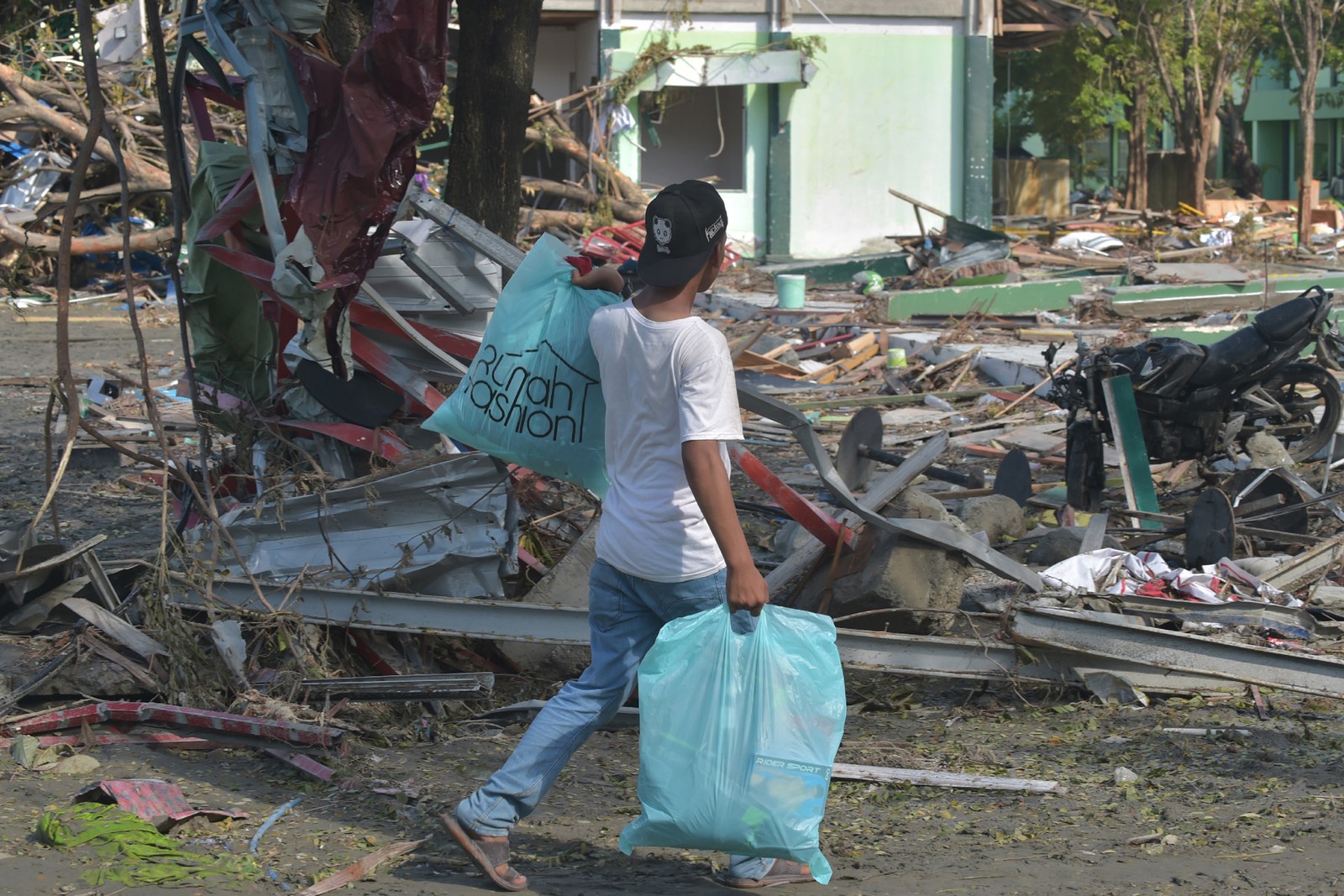 Homem caminha com sacolas após terremoto e tsunami na Indonésia