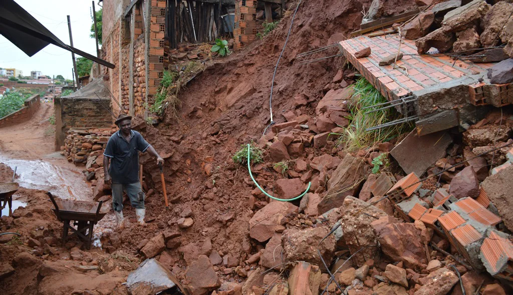 Morador retira lama do muro da sua casa