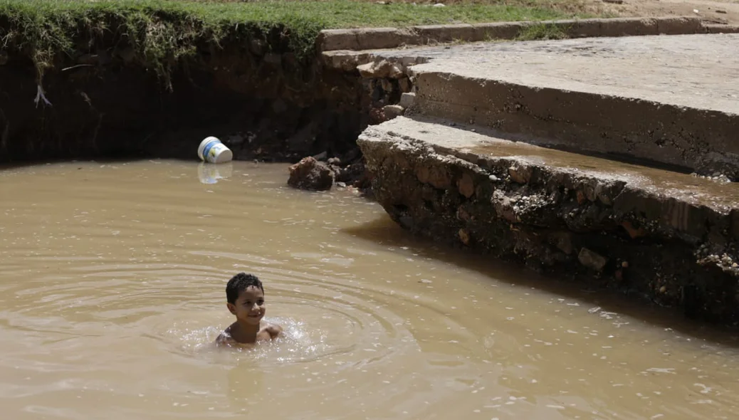 Criança tomando banho na água que se acumulou