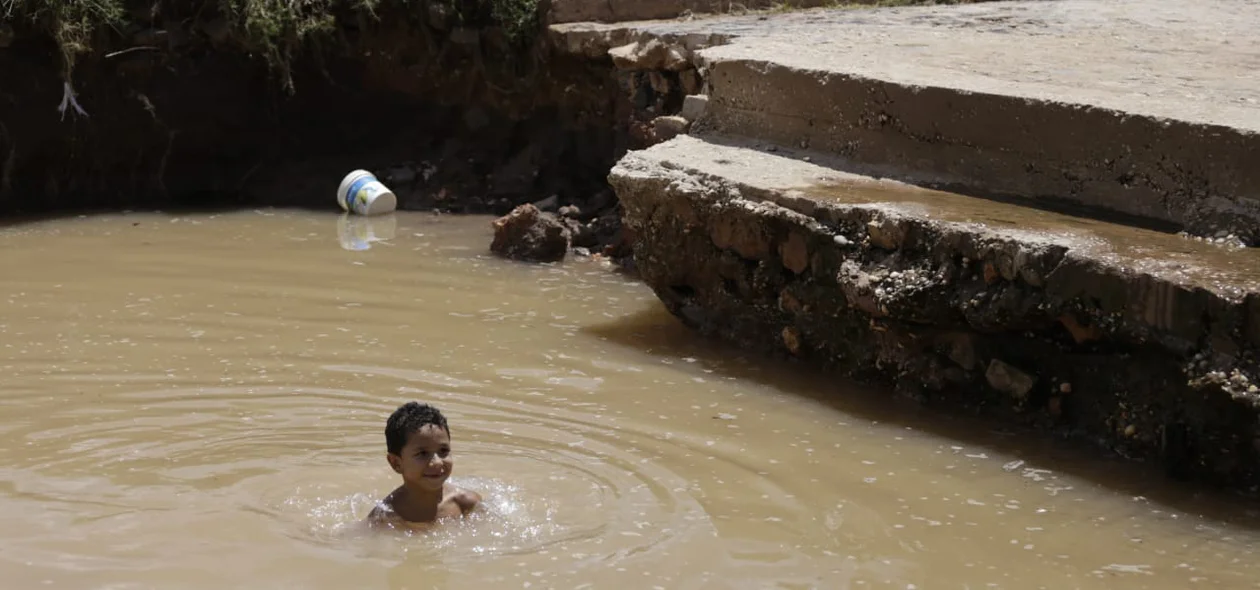 Criança tomando banho na água que se acumulou