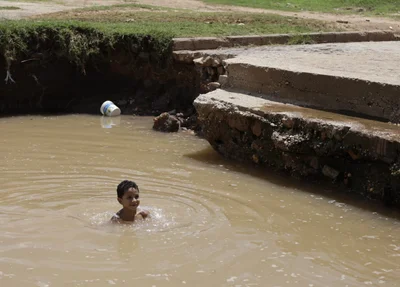 Criança tomando banho na água que se acumulou