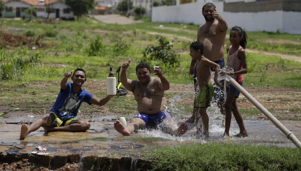 Moradores tomando banho em cano que estourou no Torquato Neto