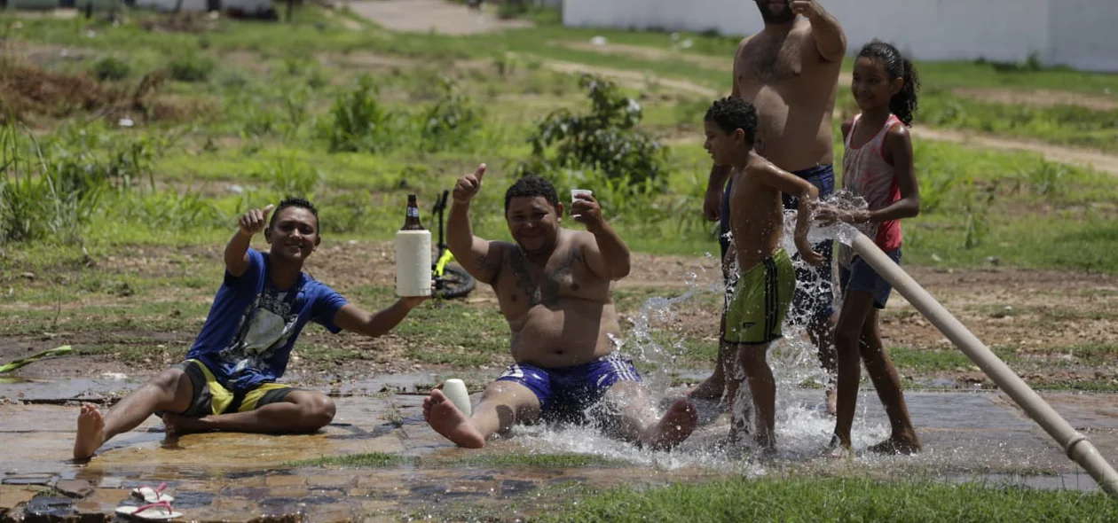 Moradores tomando banho em cano que estourou no Torquato Neto