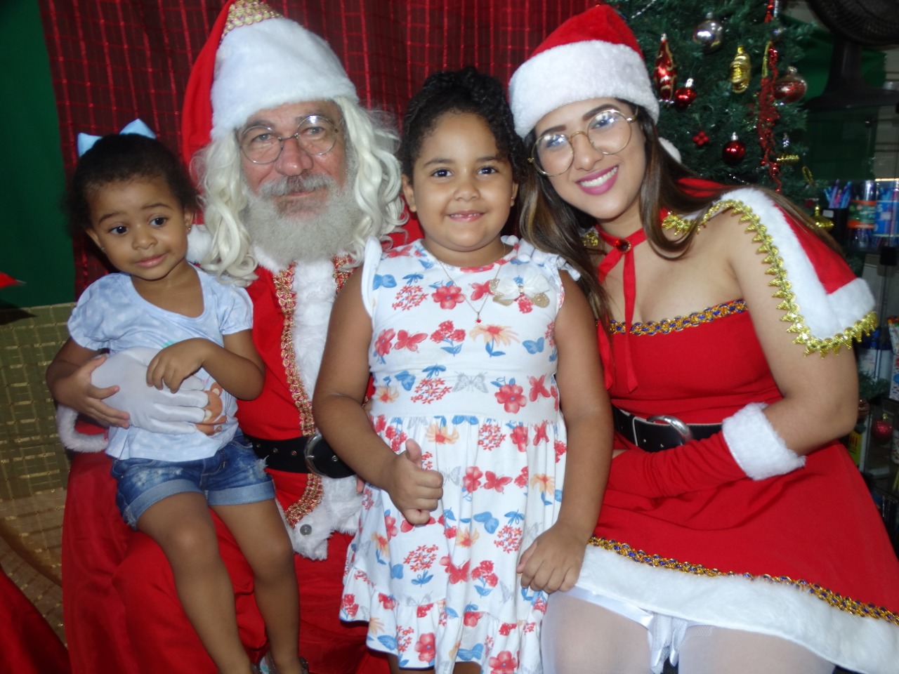 Crianças tirando foto com mamãe e papai noel 