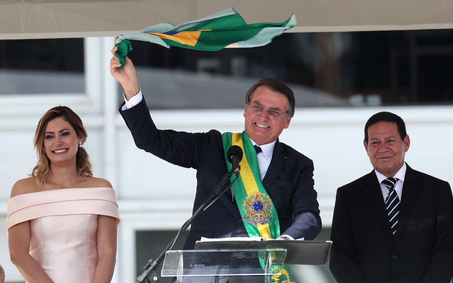Bolsonaro segura bandeira do Brasil após receber a faixa presidencial